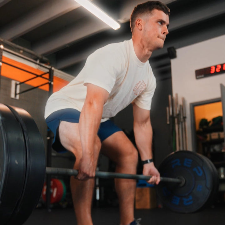 Man deadlifting in a gym, wearing navy blue FLX Pro Shorts and a white CHLKDUP tee