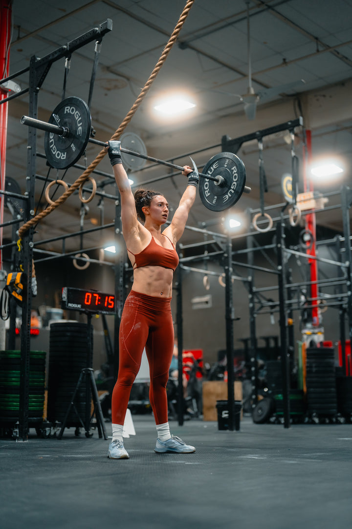 Lady lifting weights in a gym setting with equipment and flooring visible