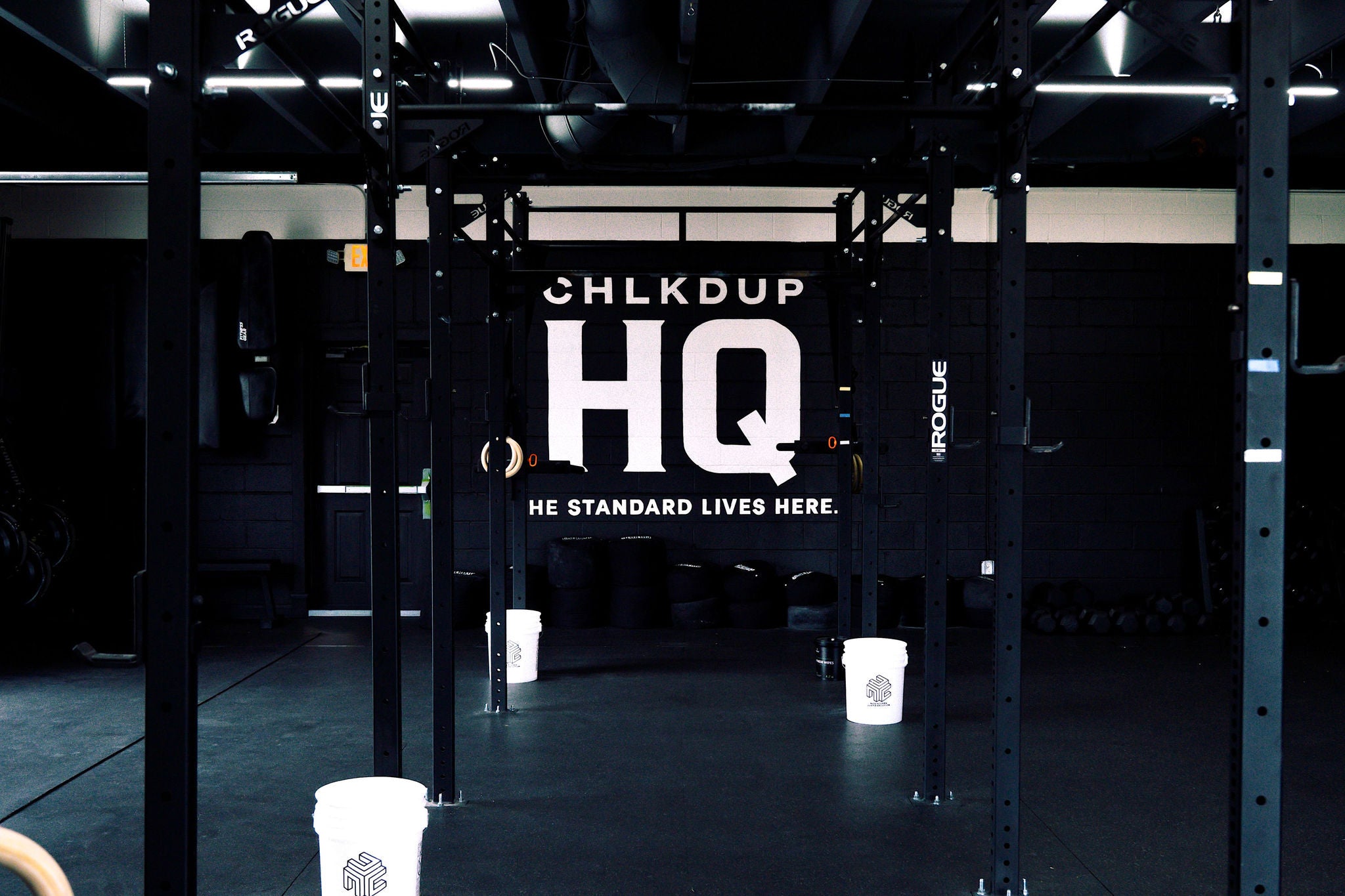 Dark gym interior with 'CHLKDUP HQ' sign and Rogue equipment.